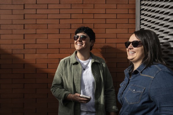 A happy curvy lesbian couple enjoying a sunny day outdoors. They are smiling, wearing casual