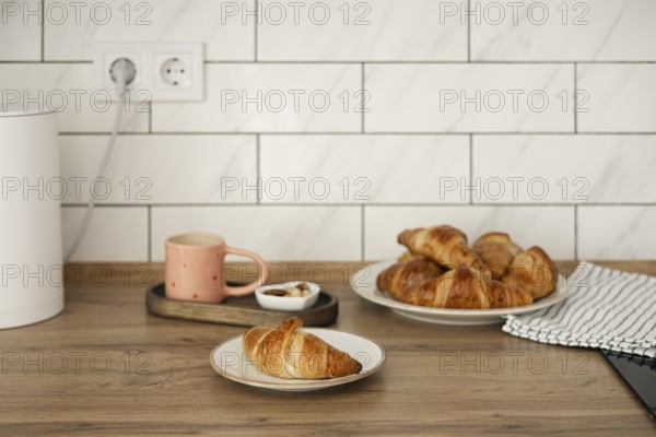 Delicious homemade croissants arranged on a rustic wooden table, captured alongside a warm cup of