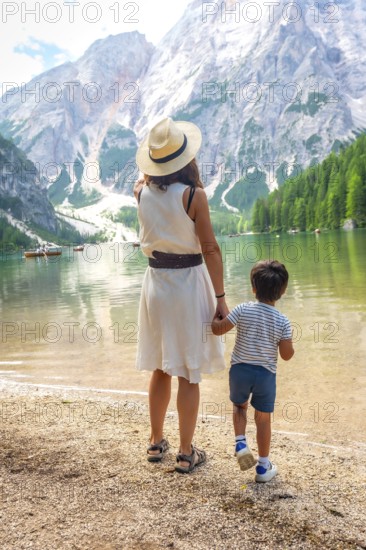 Mother and son admiring stunning panorama of lake braies, surrounded by majestic mountains and lush