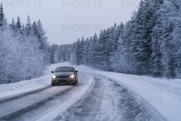 A car drives along a snow-covered road, flanked by dense, snow-laden trees in the serene Swedish