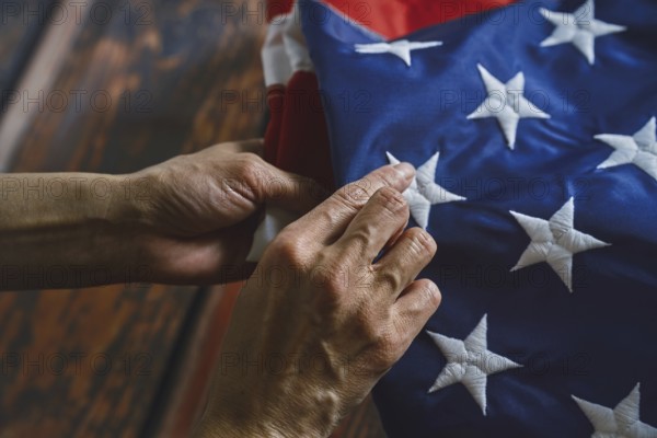 Close-up of hands reverently folding an American flag, emphasizing intricate stitching and vibrant