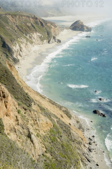 The dramatic Big Sur coastline features steep cliffs and vibrant ocean waves crashing against the