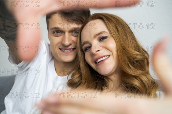 A happy couple captures a joyful moment together at home. They are smiling and relaxed, framed by