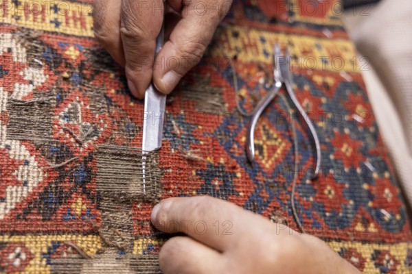 Close-up of a cropped unrecognizable senior male artisan's hands precisely restoring a colorful,