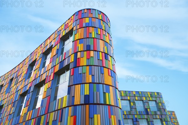 Low angle of a vibrant multicolor facade adorns a modern curved building, presenting a striking