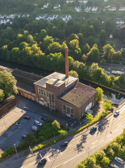 Aerial view of an industrial building on a street in a town with many trees and daylight, Calw,