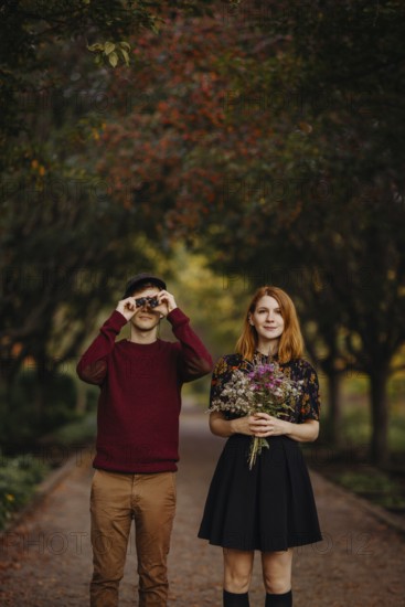 A couple enjoying a beautiful fall day in Quebec, Canada. The woman holds a bouquet of wildflowers,