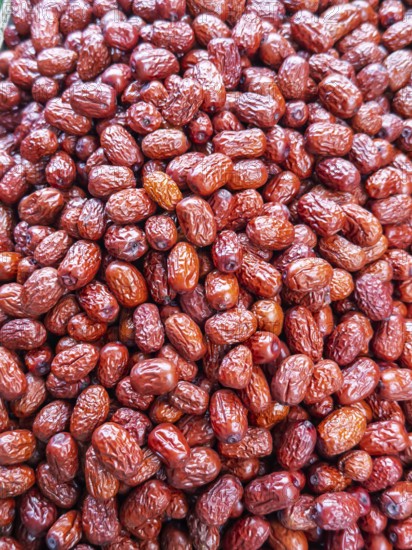 A vibrant close-up view of glossy, red jujube fruits, freshly harvested and displayed for sale at a