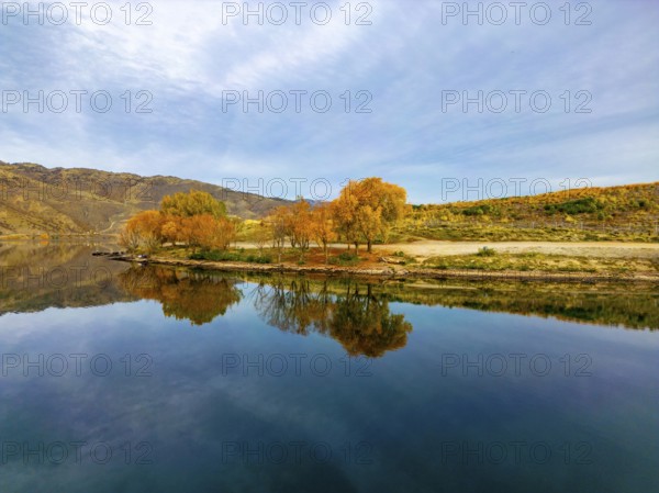 Aerial view capturing the serene beauty of Queenstown in autumn. The lake reflects the vibrant