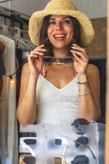 Happy tourist wearing straw hat trying on sunglasses in a souvenir shop in siargao island,