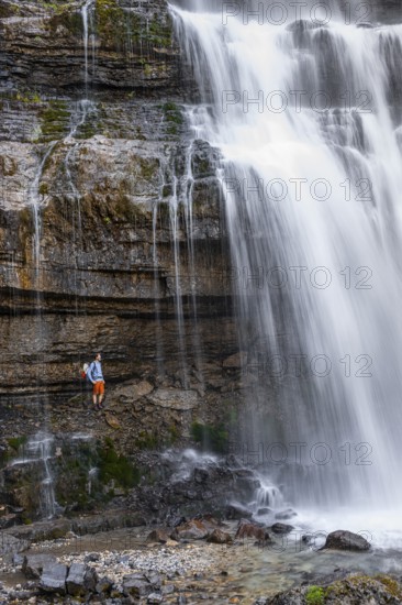 Little hiker in front of large Cascata di Mezzo waterfall, long exposure, Vallesinella, Brenta,