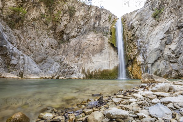 Scenic waterfall cascades into a tranquil pool surrounded by rugged rocks in Matacanes, Nuevo Leon,