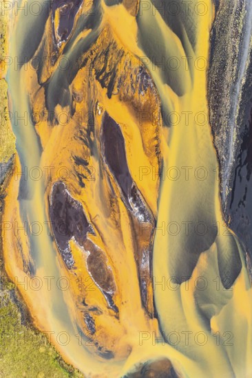 Stunning aerial shot captures the rich, golden hues of rivers snaking through the rugged terrain of