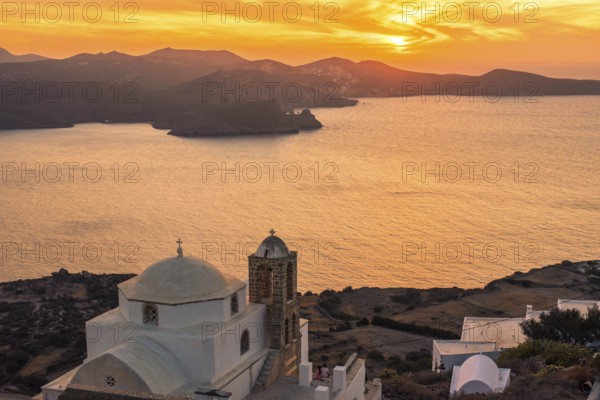 A serene sunset over the Greek coastline, featuring a classic white church with a dome in Plaka,