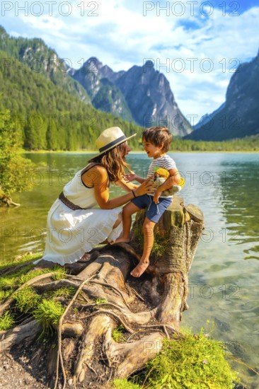 Mother and son sharing a playful moment by an alpine lake, surrounded by the breathtaking scenery