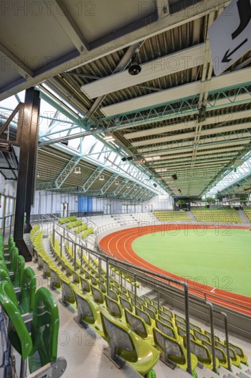 Interior view of an empty stadium with green rows of seats and an athletics track, Glaspalast,