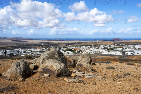 View of town, white houses of Teguise with church tower in dry volcanic landscape, view from