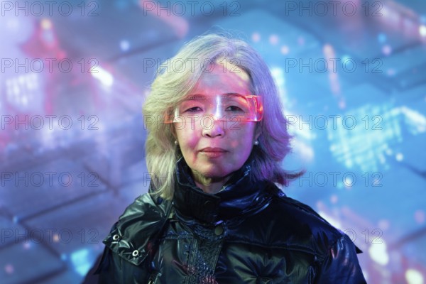 An elderly Asian woman dons futuristic eyewear, fully immersing herself in the vibrant, digital
