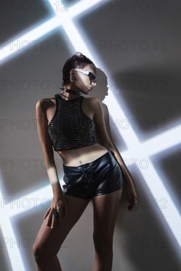 A stylish cyberpunk woman model in edgy fashion poses against a high-tech, modern backdrop. The