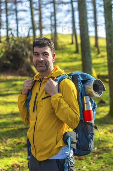Male hiker carrying a backpack, enjoying a sunny day in the forest while trekking through the