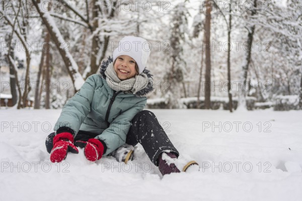 A cheerful child dressed warmly in a snowy forest, enjoying a winter day. The child wears a winter