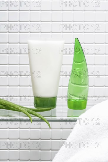 A refreshing display of a body care cream tube and a green aloe vera gel bottle, alongside a fresh