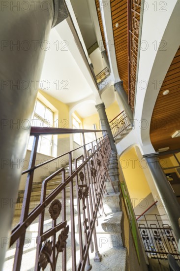 Historic staircase with arches and columns. Light falls through the windows, the structure looks