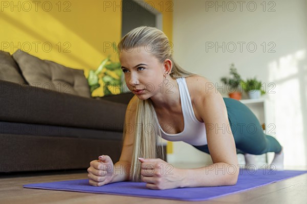 A woman performing a plank exercise on a yoga mat in her living room. Focused on core strength and
