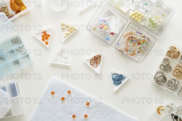 Top view of a jewelry making studio setup featuring various beads and rings in organized containers