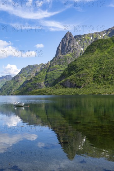 Small boats at the fjord Austnesfjorden, idyllic Norwegian fjord landscape, mountains reflected in