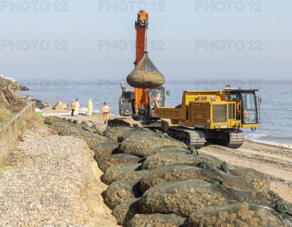 Emergency coastal defences work placing rock bags on beach to protect property, North Sea coast,