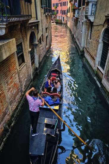 VENICE, ITALY, JUNE 27, 2018: Narrow canal between colorful old houses with gondola boat with