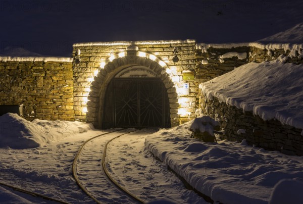 Illuminated mouth hole from Markus-Röhling-Stolln visitor mine in the snow, historical origin to