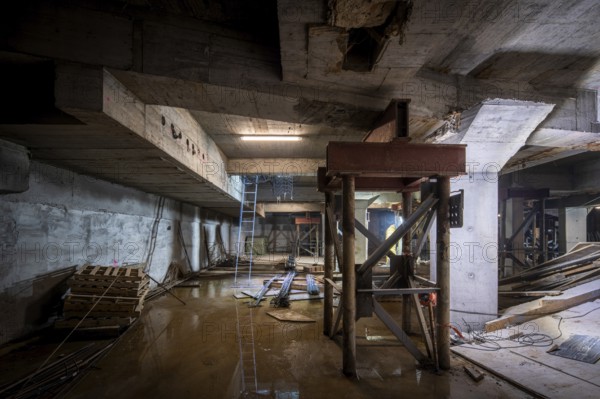 A dimly lit basement under construction, with structural beams and tools scattered about. The work