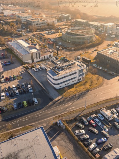 Aerial view of an urban industrial area with buildings and car parks under an orange sky,