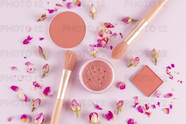 Aesthetic flat lay of pink makeup brushes and cosmetics surrounded by delicate rose petals on a