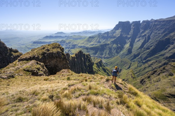 Young hiker looking at the impressive mountains and cliffs of the Drakensberg Mountains, hiking