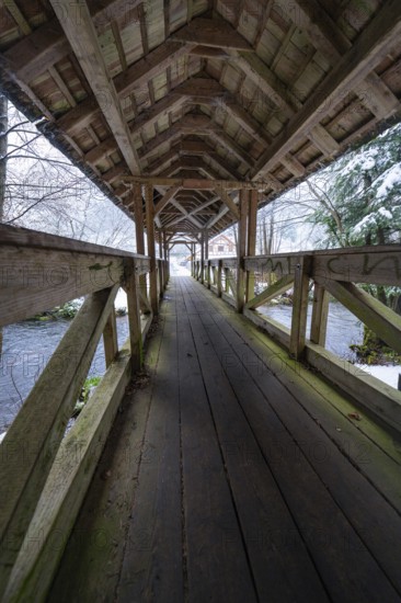 Long walkway of a wooden bridge over a wintry river course, Kälberbrücke, Enzklösterle, Calw