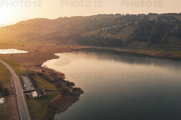 Valley with quiet lake and surrounding landscape in the warm light of sunset, Großer Alpsee,