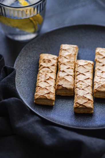 Crisp, golden puff pastry filled with sweet apricot jam, artfully arranged on a sleek black plate.