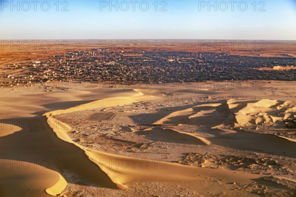 Desert town on the edge of the sand dunes, in the foreground extensive dune landscape, The dunes of