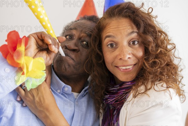 A joyful moment at a birthday celebration featuring two people wearing colorful party hats and
