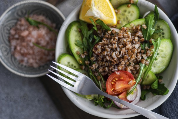 A nutritious lunch is prepared with fresh rocket, chopped oregano, cherry tomatoes, cucumber,