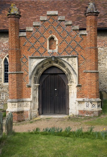 Tudor red brick porch set against more ancient building. St Peter's church, Charsfield Suffolk,