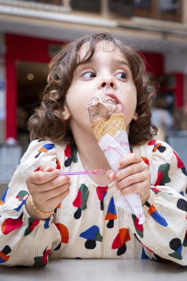 A young girl delights in a chocolate ice cream cone, savoring every bite on a sunny day in a