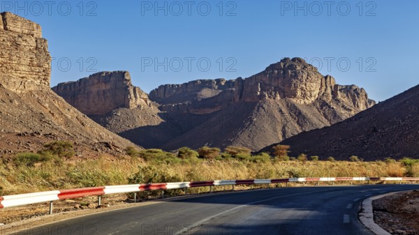 A road with a bend winds its way through impressive mountain scenery in a barren desert landscape