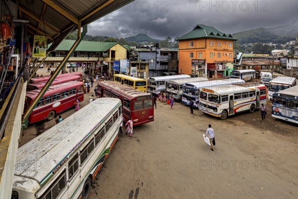 Several buses at a bus stop with people and mountainous landscape in the background, Nuwara Eliya