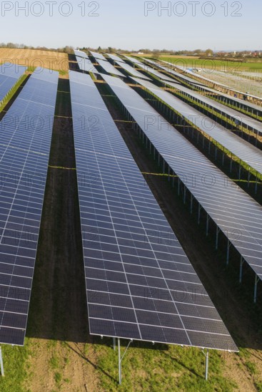 Close view of solar panels in orderly rows over green field, Agri PV Bau für Landwirtschaft,