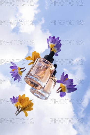 A glass skincare bottle with black dropper cap are showcased among colorful flowers, set against a