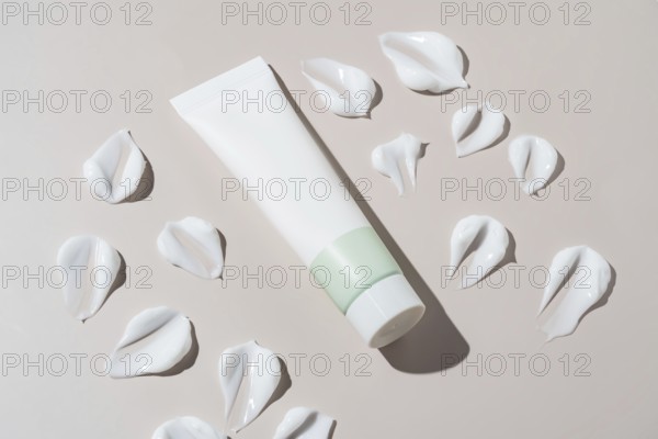 An elegant cosmetics container with a minimalist design appears next to artistic cream stains on a
